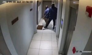 Capture supposée de vidéosurveillance dans un couloir d’hôtel avec une porte de chambre.